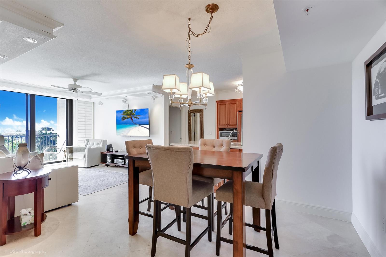A dining area with a wooden table and chairs sits before an open-concept living room — 651 Okeechobee Boulevard # 509, West Palm Beach FL 33401, WEST PALM BEACH, FL