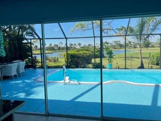 A view through a glass door shows a swimming pool inside a screened-in lanai — 2091 KING TARPON DRIVE, PUNTA GORDA, FL