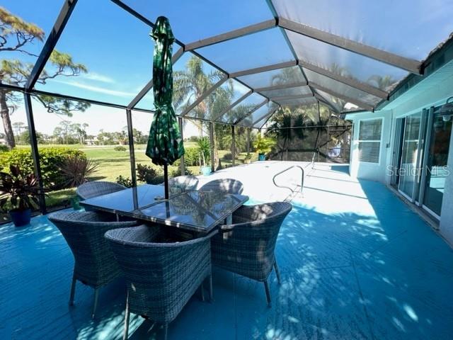 A screened-in patio features a dining set, a green umbrella, and a blue floor — 2091 KING TARPON DRIVE, PUNTA GORDA, FL