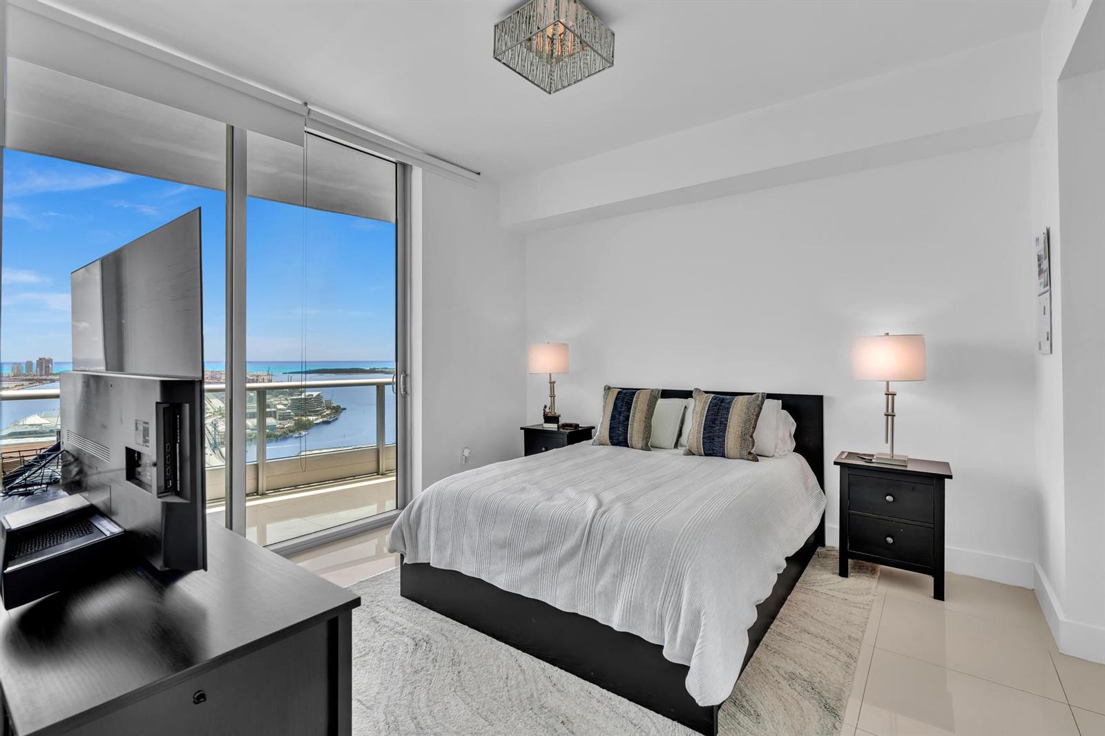 A bedroom features a bed, two nightstands, a television, and a balcony with water views — 900 Biscayne Boulevard # 4703, Miami FL 33132, MIAMI, FL
