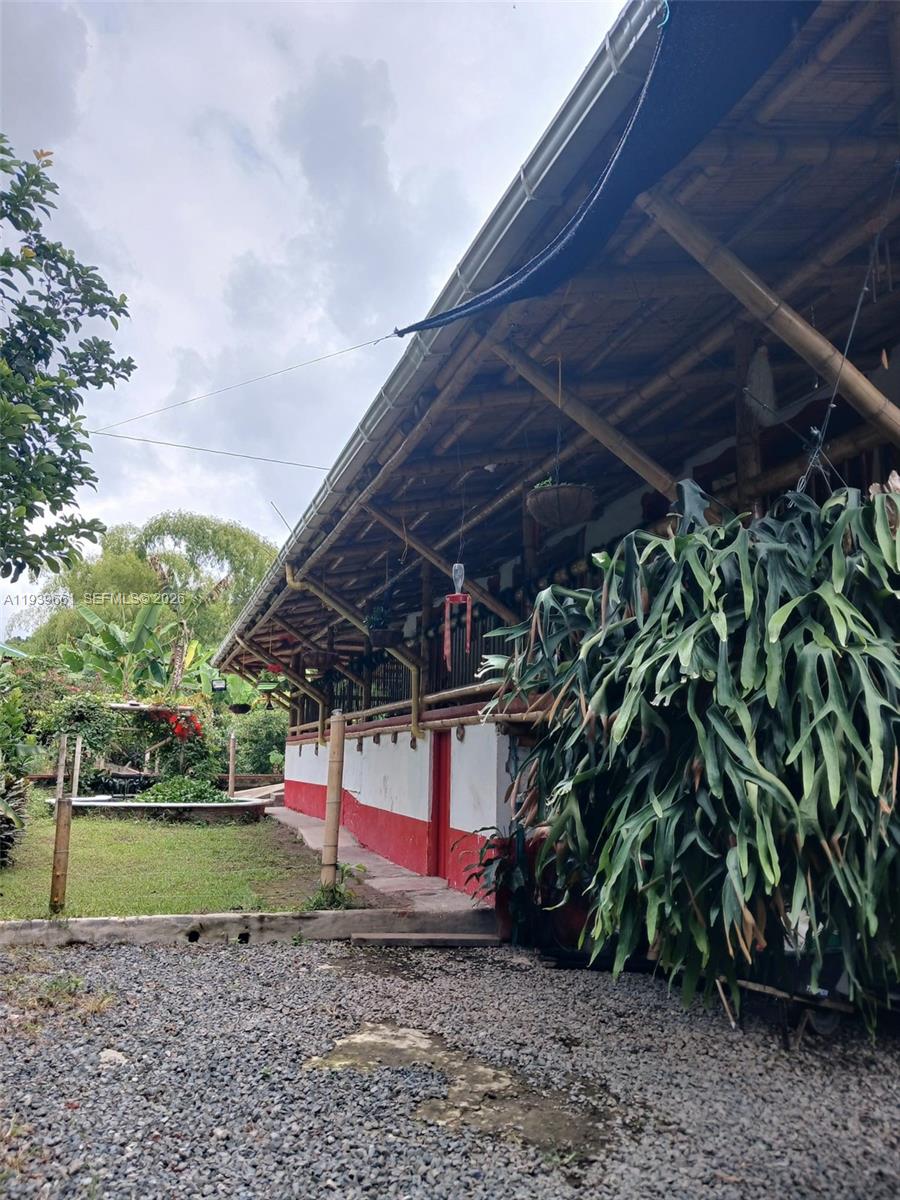A rustic building with a bamboo roof and red-and-white exterior walls sits beside a garden — Quimbaya Colombia, FL 0, FL