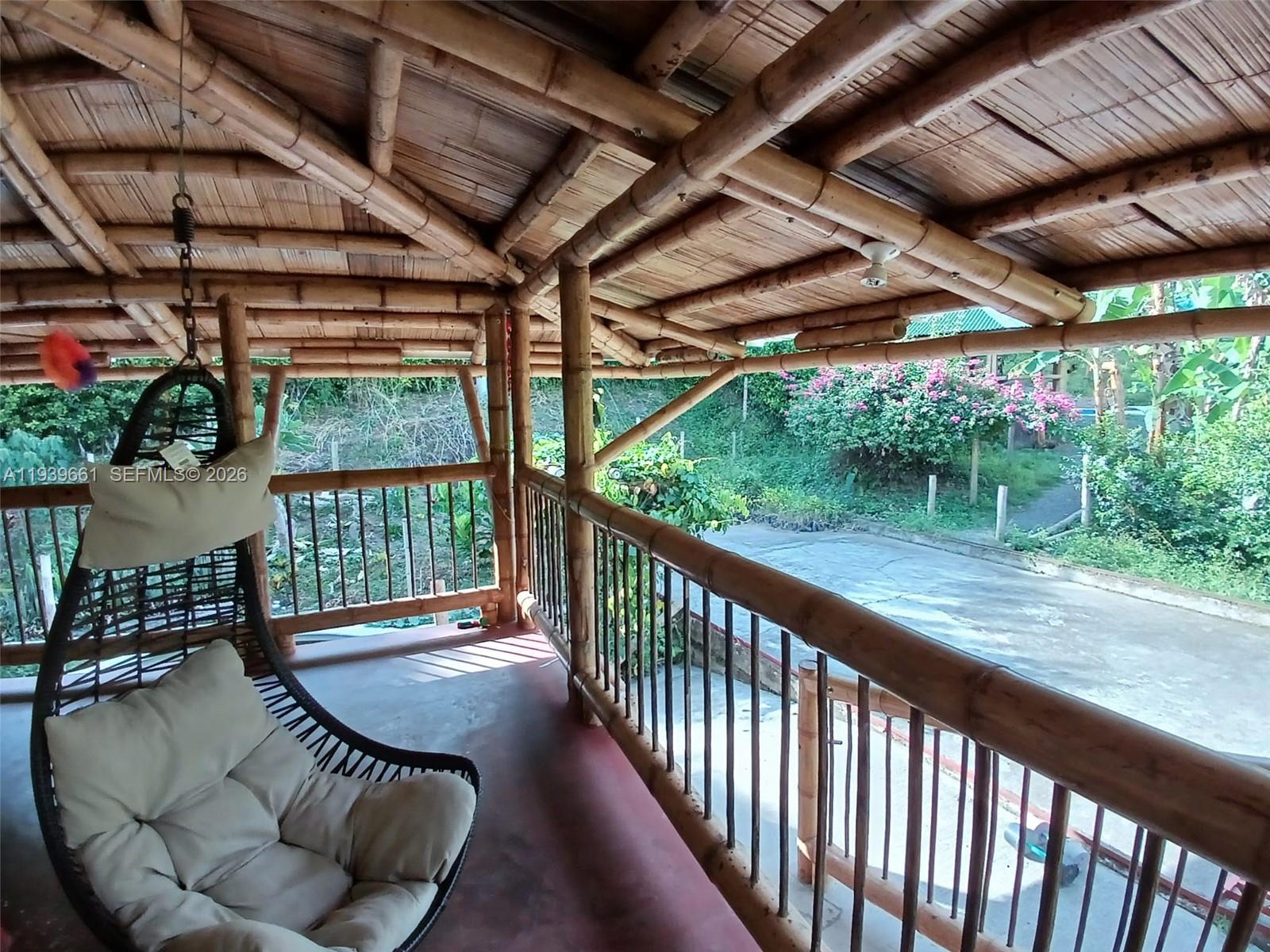 A covered bamboo porch features a hanging chair and a view of a garden — Quimbaya Colombia, FL 0, FL