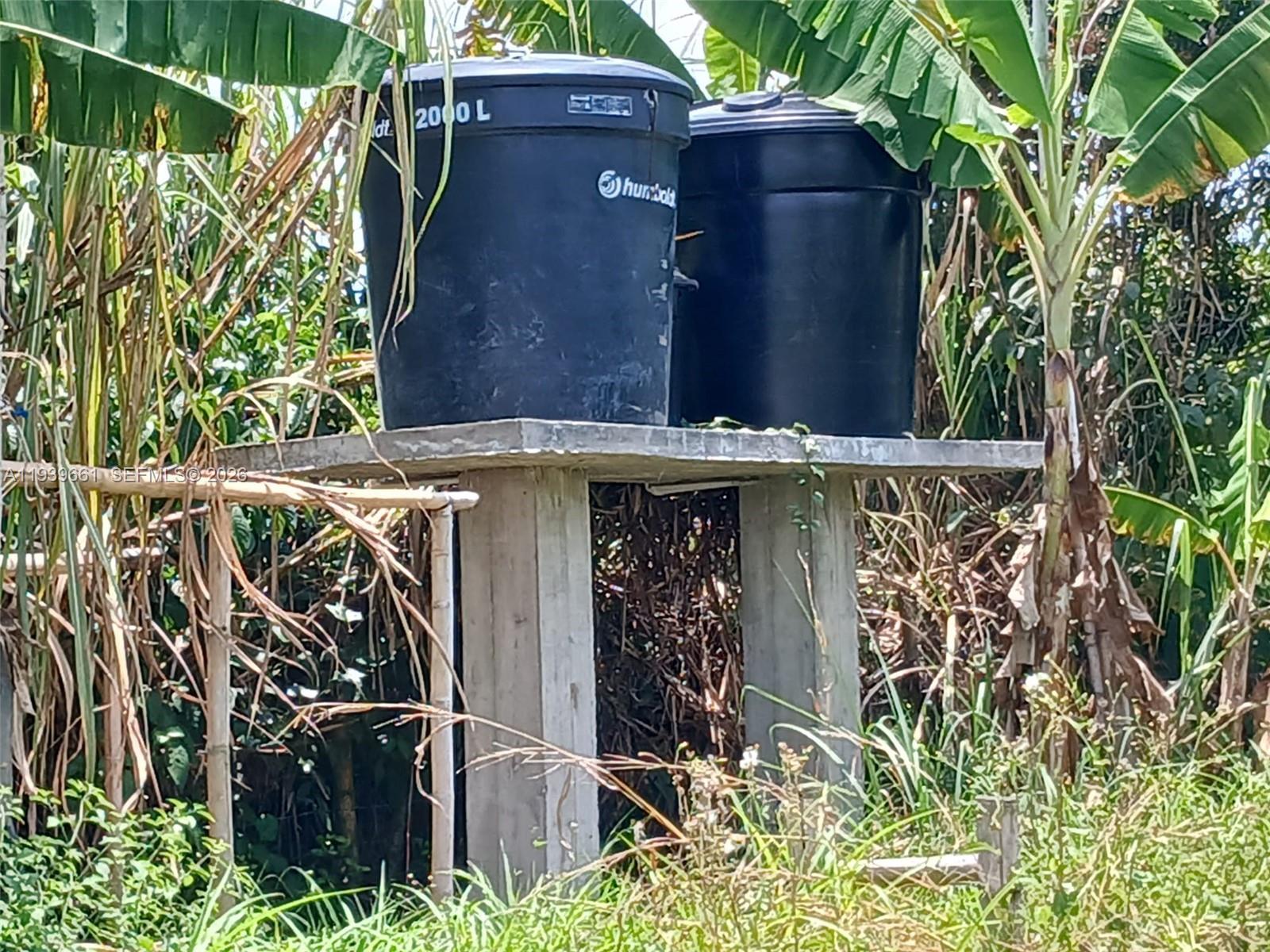 Two large black water tanks sit on a concrete platform supported by concrete pillars outdoors — Quimbaya Colombia, FL 0, FL