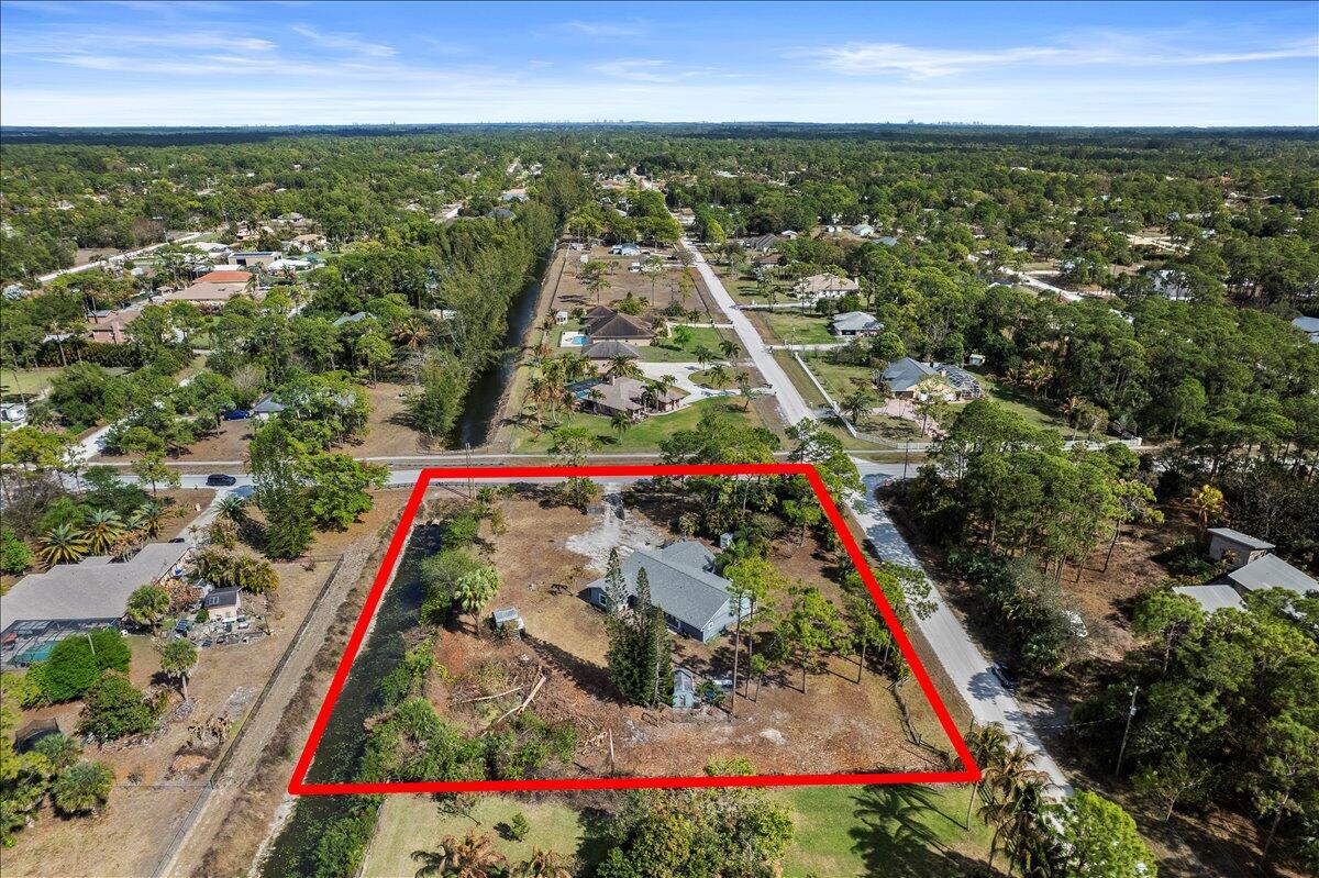 An aerial view shows a single-story house on a large, partially wooded lot with a canal — 14537 77th Place N, Loxahatchee FL 33470, LOXAHATCHEE, FL
