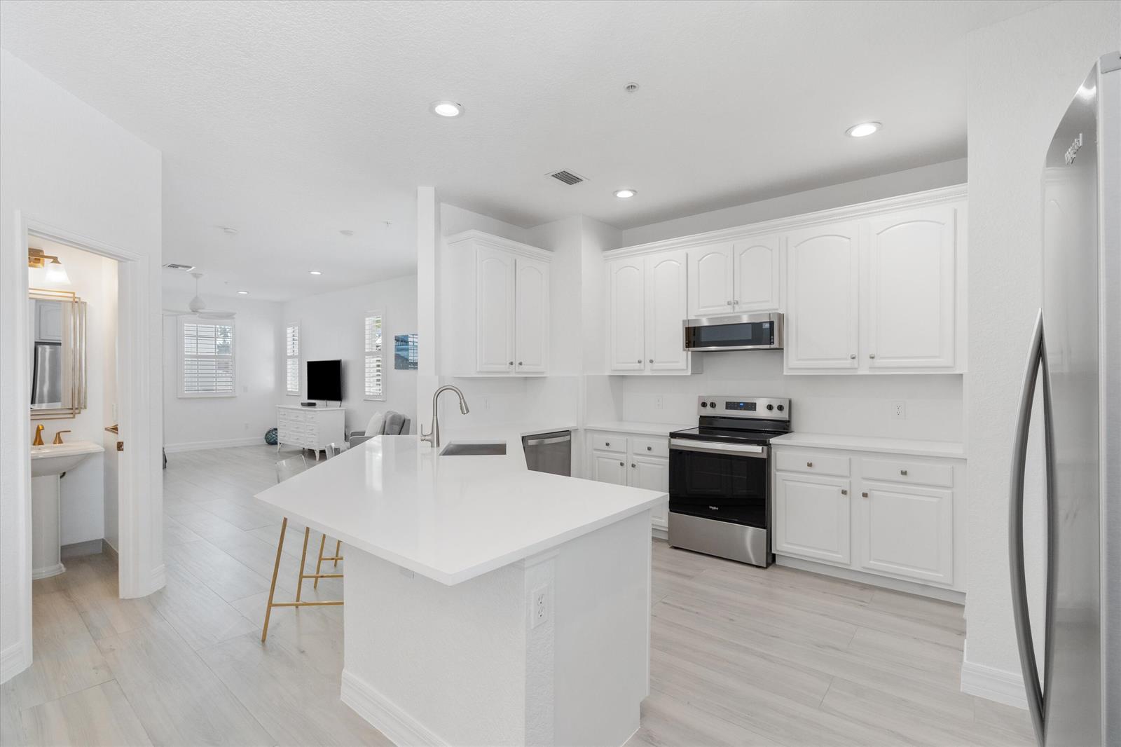 A bright kitchen features white cabinets, stainless steel appliances, and a central quartz island — 295 NE 5th Avenue # 32, Delray Beach FL 33483, DELRAY BEACH, FL