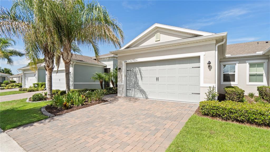 A single-story house with a paved driveway, a two-car garage, and a palm tree — 1896 FLORA PASS PLACE, KISSIMMEE, FL