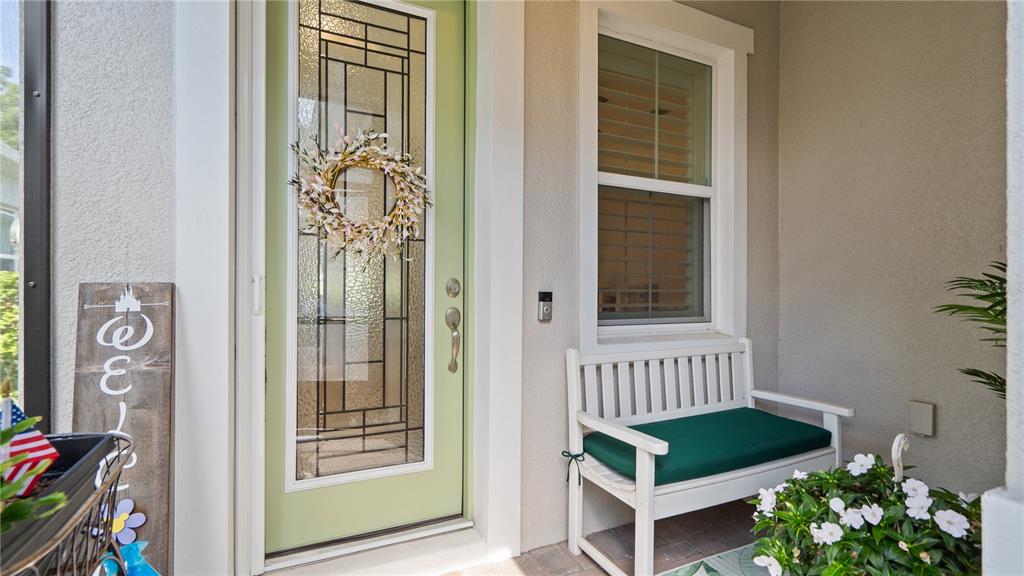 A light green front door with a glass insert sits beside a white wooden bench — 1896 FLORA PASS PLACE, KISSIMMEE, FL