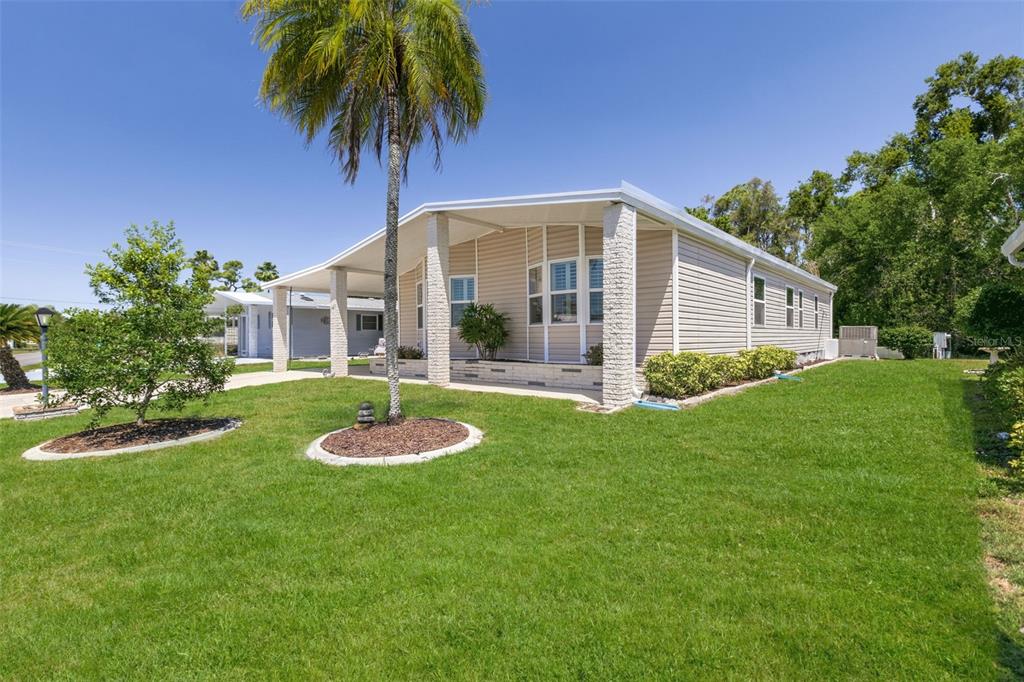 A single-story manufactured home with beige siding and a palm tree in the front yard — 209 VISTORIA DRIVE, NORTH PORT, FL