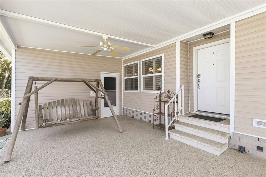 A covered porch features a wooden swing, a white front door, and beige siding — 209 VISTORIA DRIVE, NORTH PORT, FL