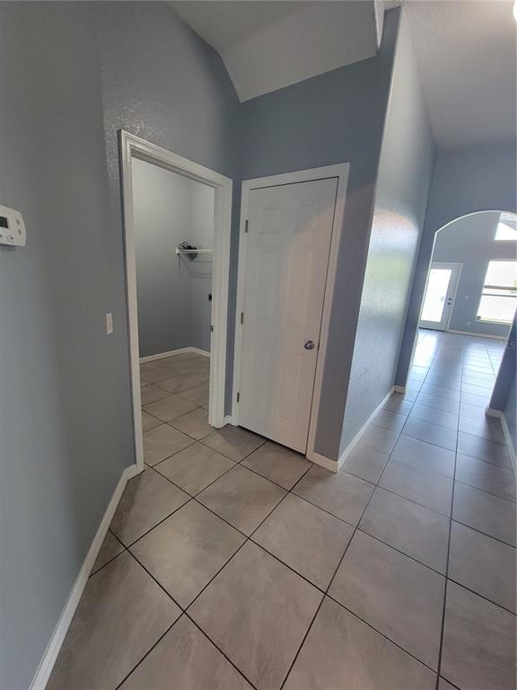A hallway with tiled floors leads to an arched entryway and two interior doors — 2734 ROCHELLE DRIVE, WINTER HAVEN, FL