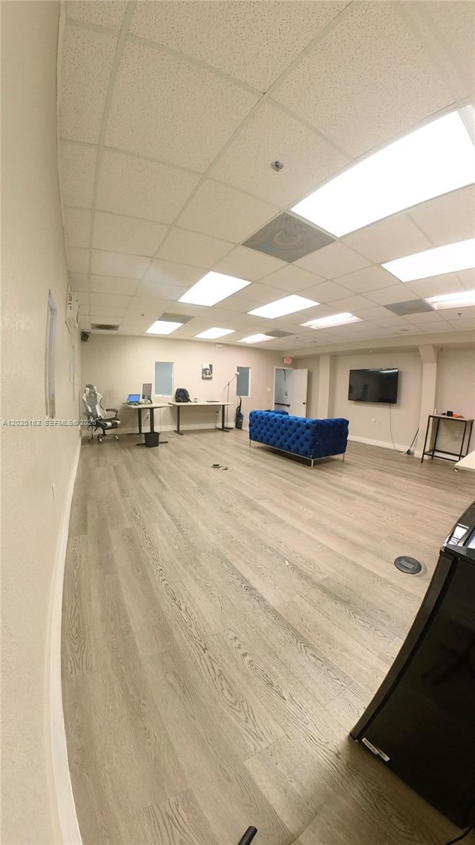 A spacious office room features light wood-look flooring, a blue sofa, and drop ceiling panels — 2746 NW 112th Ave # 2746, Doral FL 33172, DORAL, FL