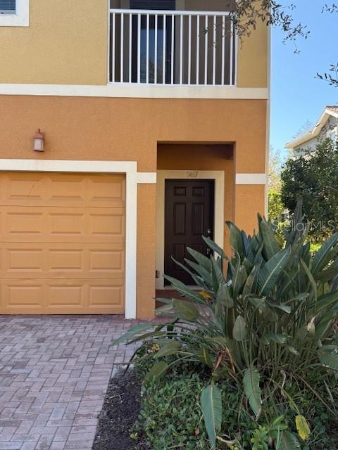 An exterior view of a two-story tan townhouse with a garage and a balcony — 5467 SOAPSTONE PLACE UNIT 203, SARASOTA, FL