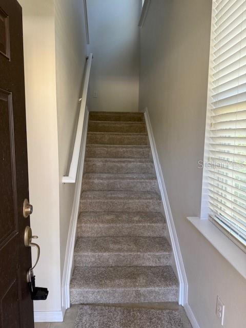 A carpeted staircase leads upward from an entryway with a window and a door — 5467 SOAPSTONE PLACE UNIT 203, SARASOTA, FL
