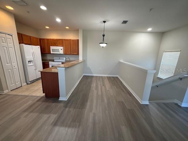 A kitchen with wood cabinets and a breakfast bar overlooks an open dining area — 5467 SOAPSTONE PLACE UNIT 203, SARASOTA, FL