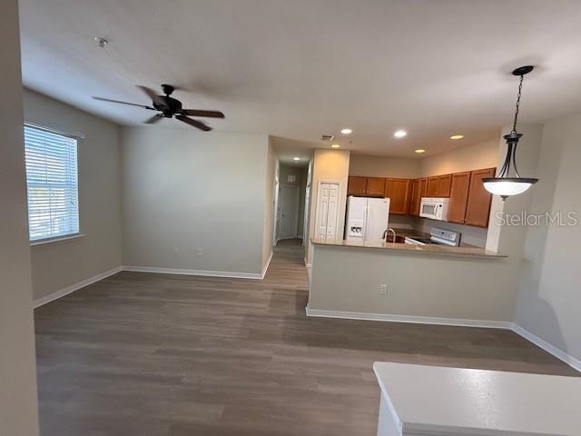 An open-concept living area features wood-look flooring, a ceiling fan, and a kitchen with wood cabinets — 5467 SOAPSTONE PLACE UNIT 203, SARASOTA, FL