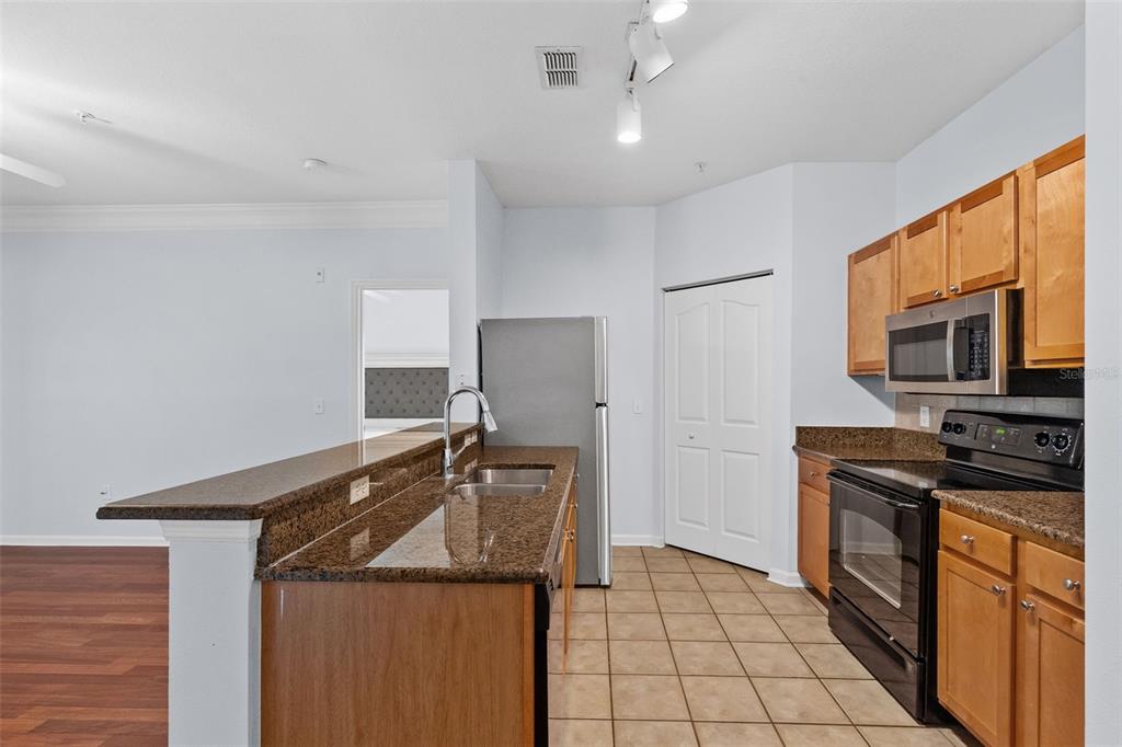A kitchen features brown granite countertops, wood cabinets, black appliances, and tile flooring — 4207 S DALE MABRY HIGHWAY UNIT 5310, TAMPA, FL