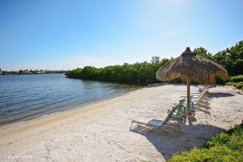 A sandy beach features a thatched-roof umbrella and several lounge chairs by the water — 1000 Scotia Drive # 304, Hypoluxo FL 33462, HYPOLUXO, FL