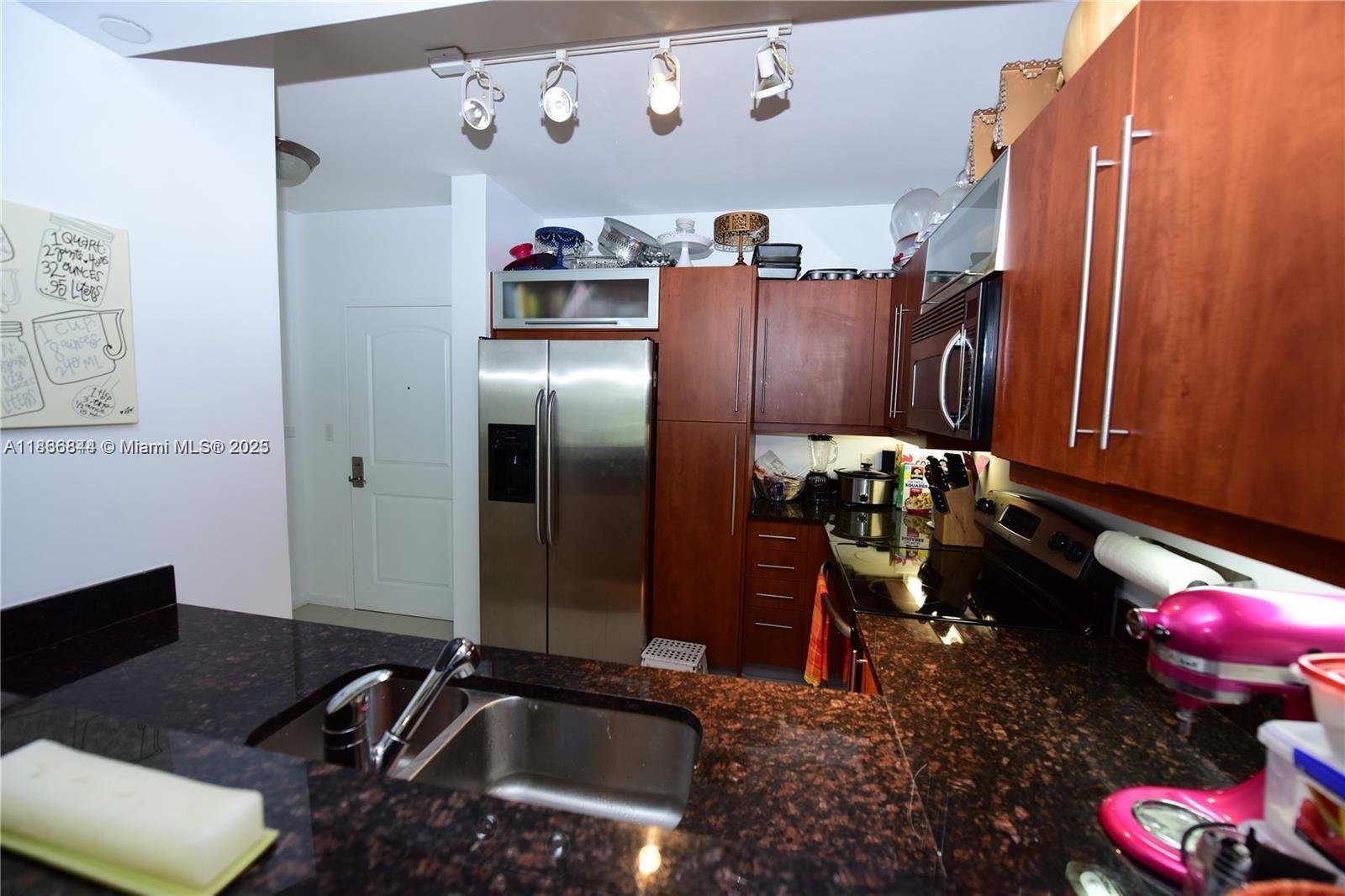 A kitchen features dark granite countertops, stainless steel appliances, and wood cabinetry — 7355 SW 89th St # 622N, Miami FL 33156, MIAMI, FL