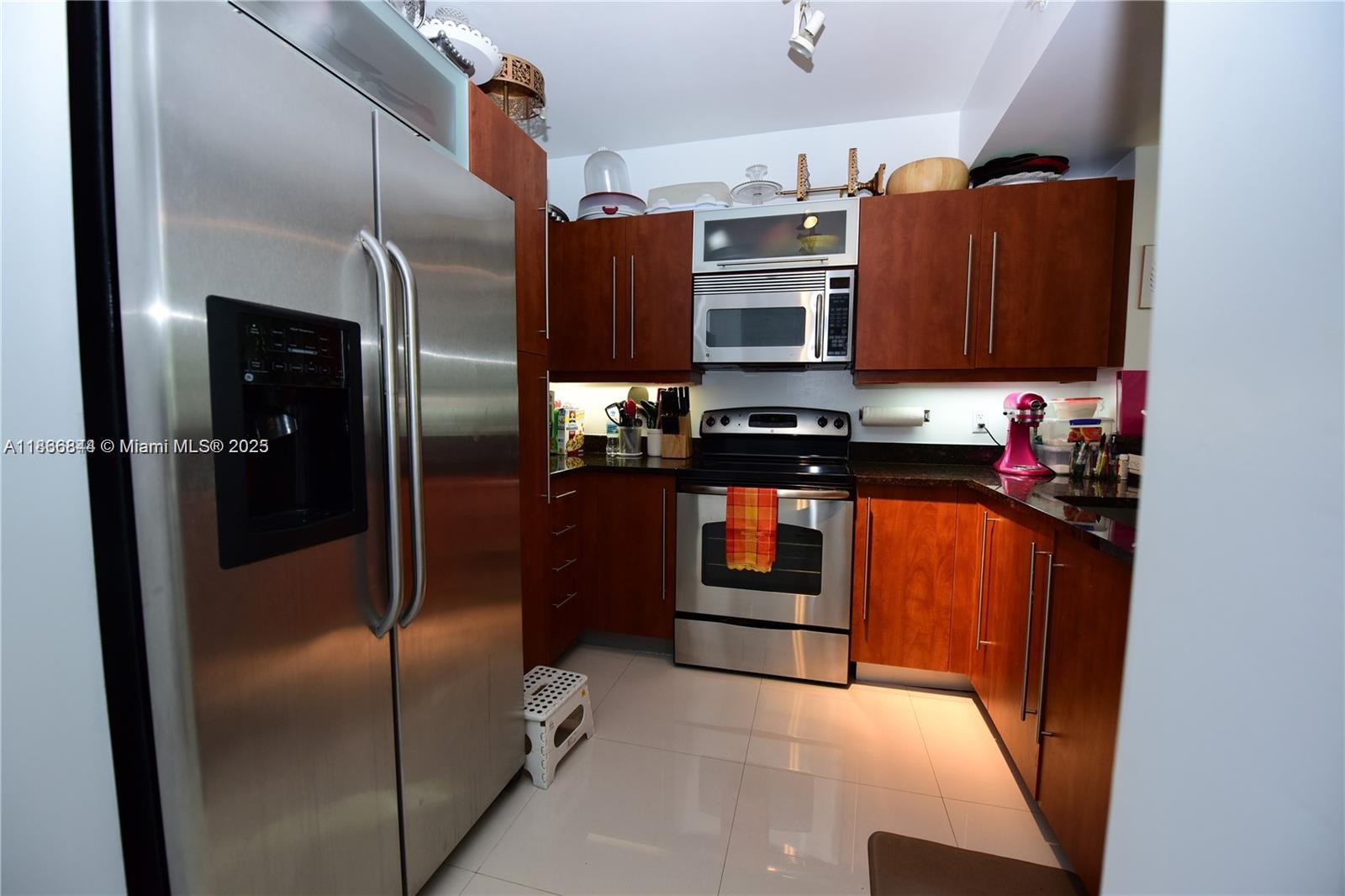 A kitchen features stainless steel appliances, dark wood cabinets, and light-colored tile flooring — 7355 SW 89th St # 622N, Miami FL 33156, MIAMI, FL