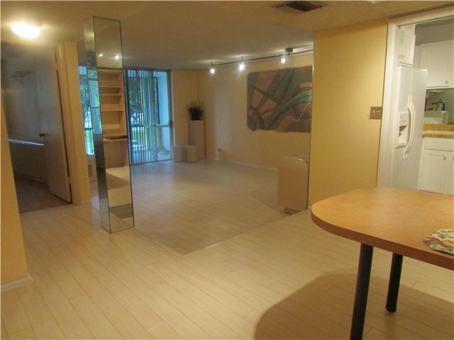 A view of a living area with light-colored flooring, a mirrored column, and a kitchen — 3660 Inverrary Drive # 2f, Lauderhill FL 33319, LAUDERHILL, FL