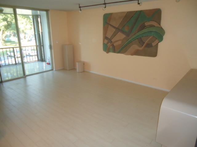 An empty room with light wood flooring, peach walls, and a large abstract wall sculpture — 3660 Inverrary Drive # 2f, Lauderhill FL 33319, LAUDERHILL, FL