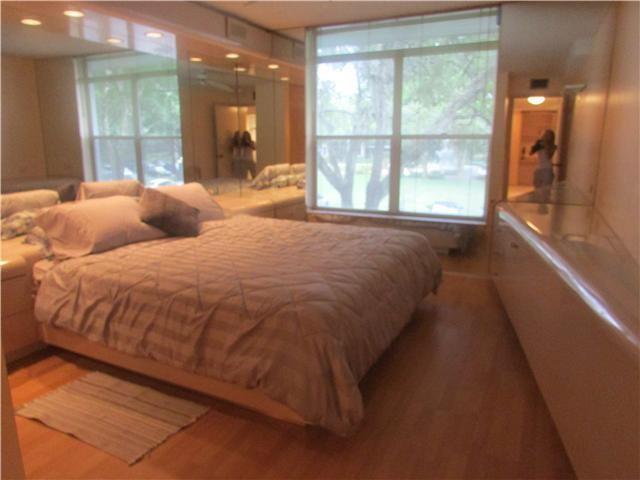A bedroom features a bed with a quilted cover, wood flooring, and large windows — 3660 Inverrary Drive # 2f, Lauderhill FL 33319, LAUDERHILL, FL