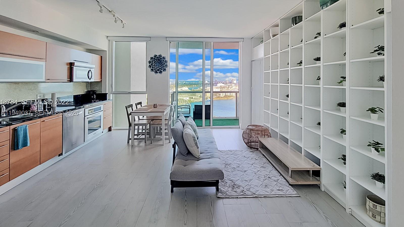 An open-concept living area features a kitchen, dining space, and a wall of white shelving — 253 NE 2nd St # 3305, Miami FL 33132, MIAMI, FL