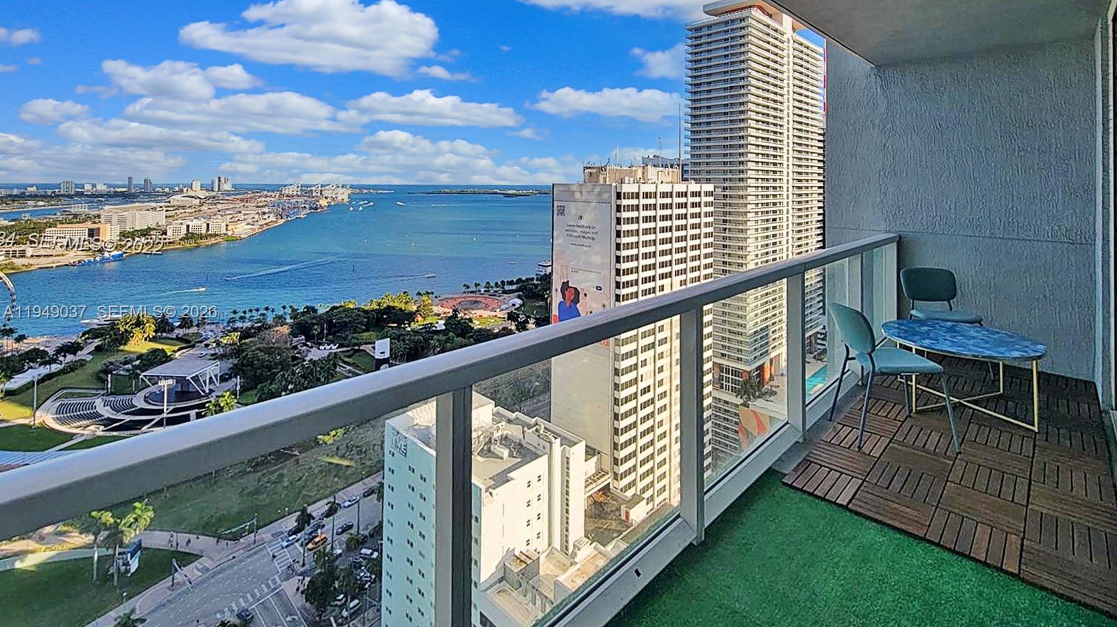 A high-rise balcony features artificial turf, wood tiles, a small table, and a water view — 253 NE 2nd St # 3305, Miami FL 33132, MIAMI, FL