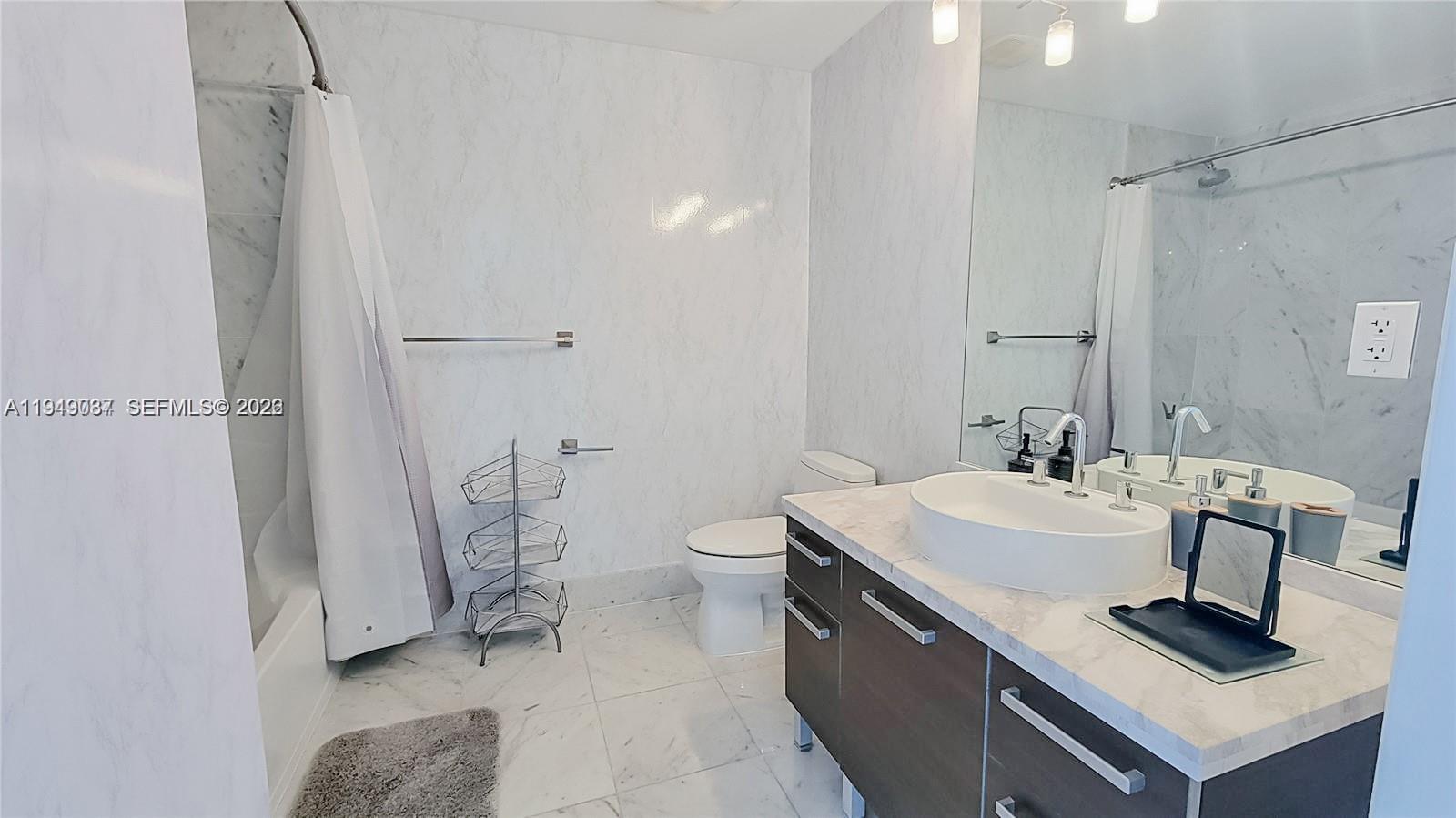 A bathroom features a marble-tiled shower, a white vessel sink, and a dark wood vanity — 253 NE 2nd St # 3305, Miami FL 33132, MIAMI, FL