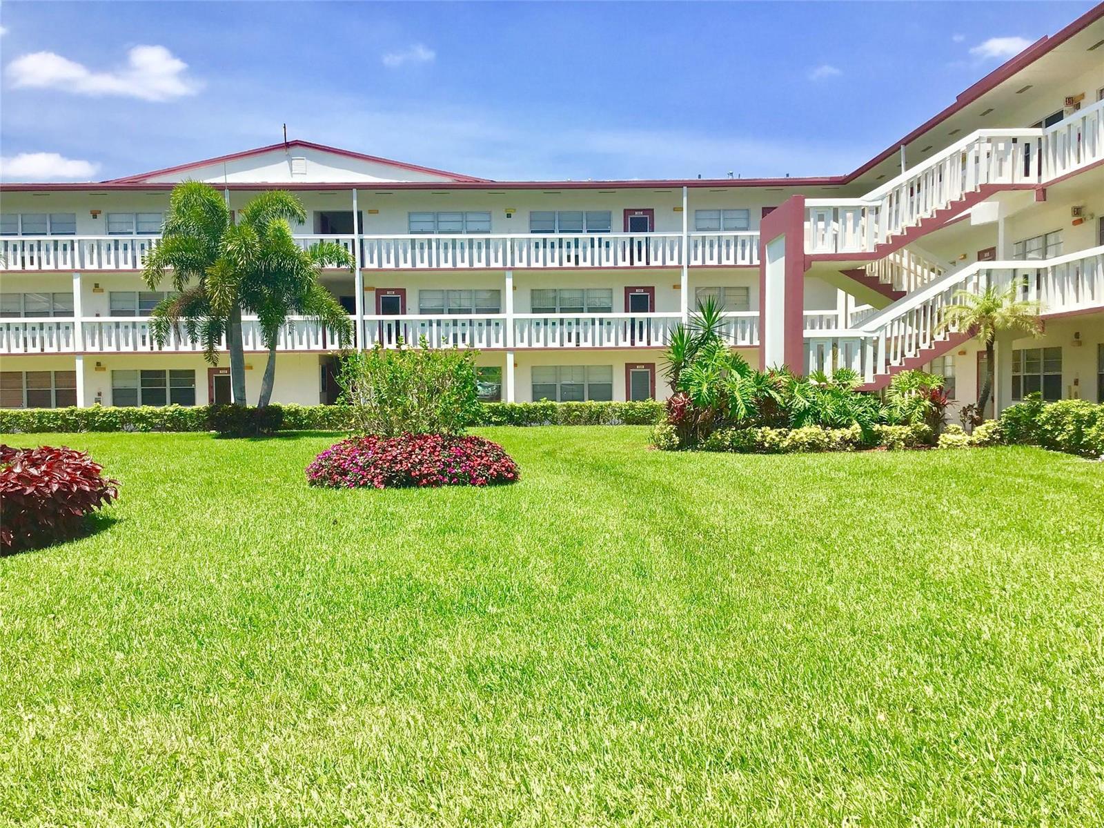 A three-story apartment building with white balconies and a large green lawn in front — 135 Fanshaw D # 135, Boca Raton FL 33434, BOCA RATON, FL