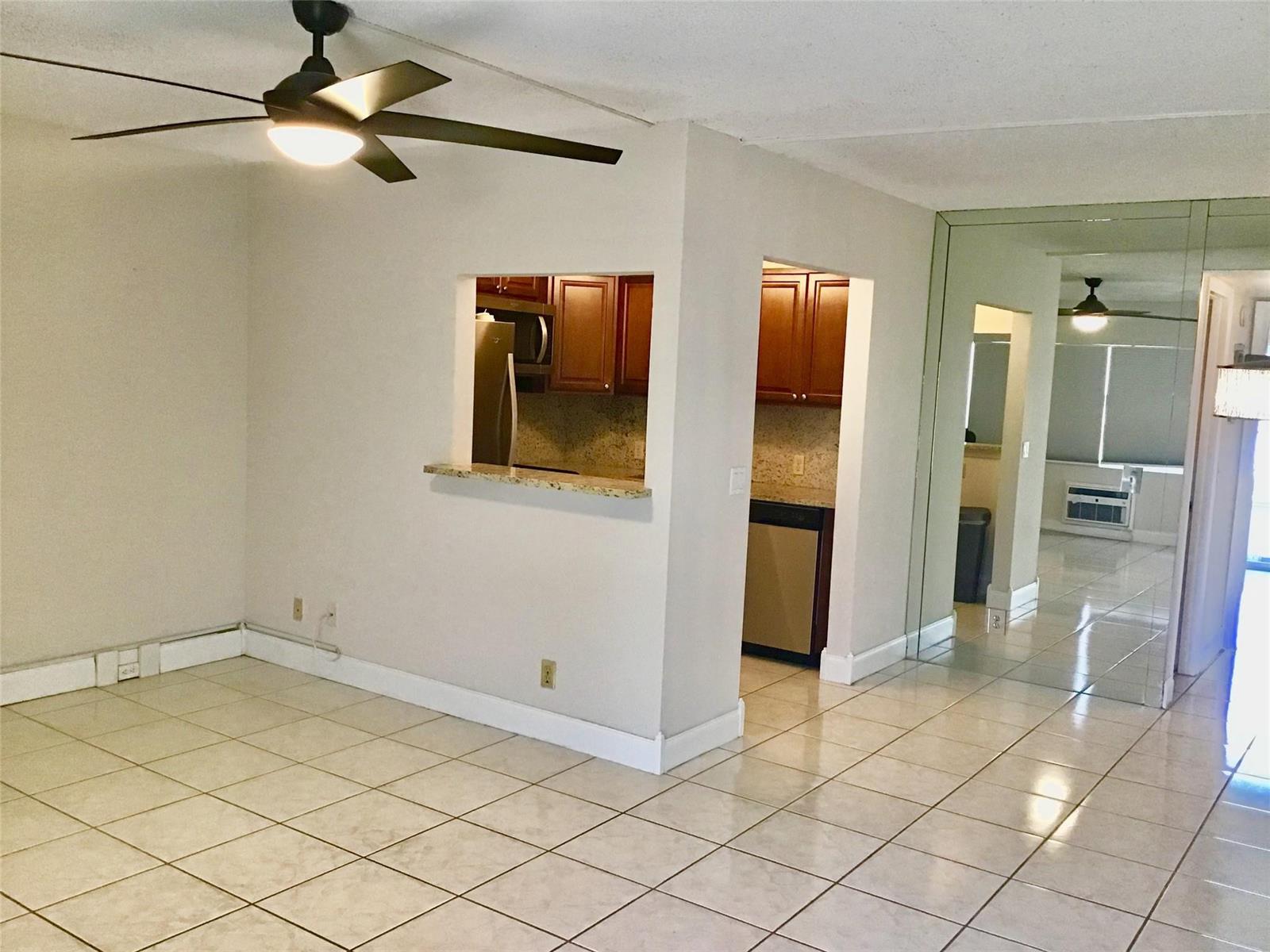 An interior view showing a tiled living area with a ceiling fan and kitchen pass-through — 135 Fanshaw D # 135, Boca Raton FL 33434, BOCA RATON, FL