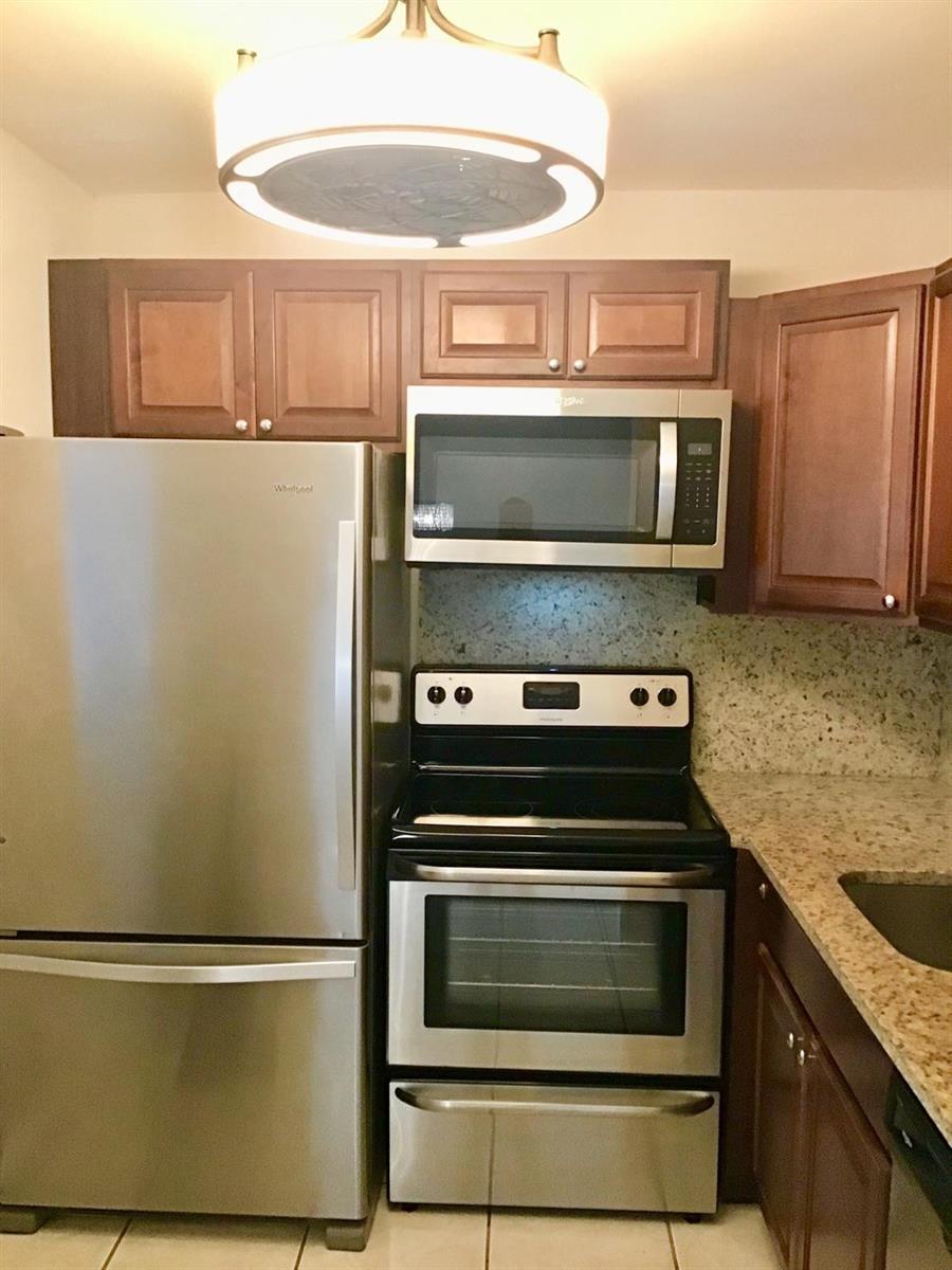 A kitchen features stainless steel appliances, dark wood cabinets, and speckled granite countertops — 135 Fanshaw D # 135, Boca Raton FL 33434, BOCA RATON, FL