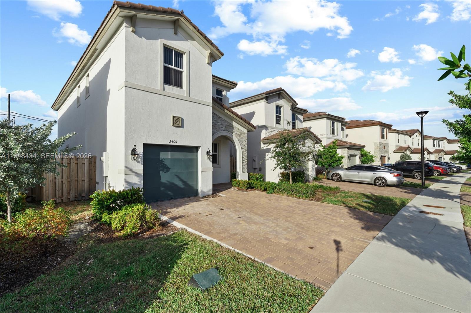 A two-story suburban house with a paved driveway, garage, and light-colored stucco exterior — 2405 NW 131st Cir, Miami FL 33167, MIAMI, FL