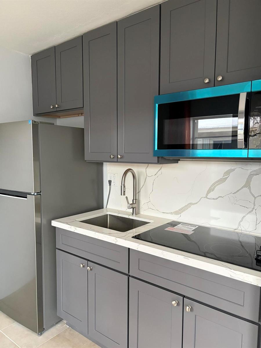 A kitchen features gray shaker cabinets, a stainless steel refrigerator, and a marble-patterned countertop — 1017 SE 3rd Street # 4, Deerfield Beach FL 33441, DEERFIELD BEACH, FL