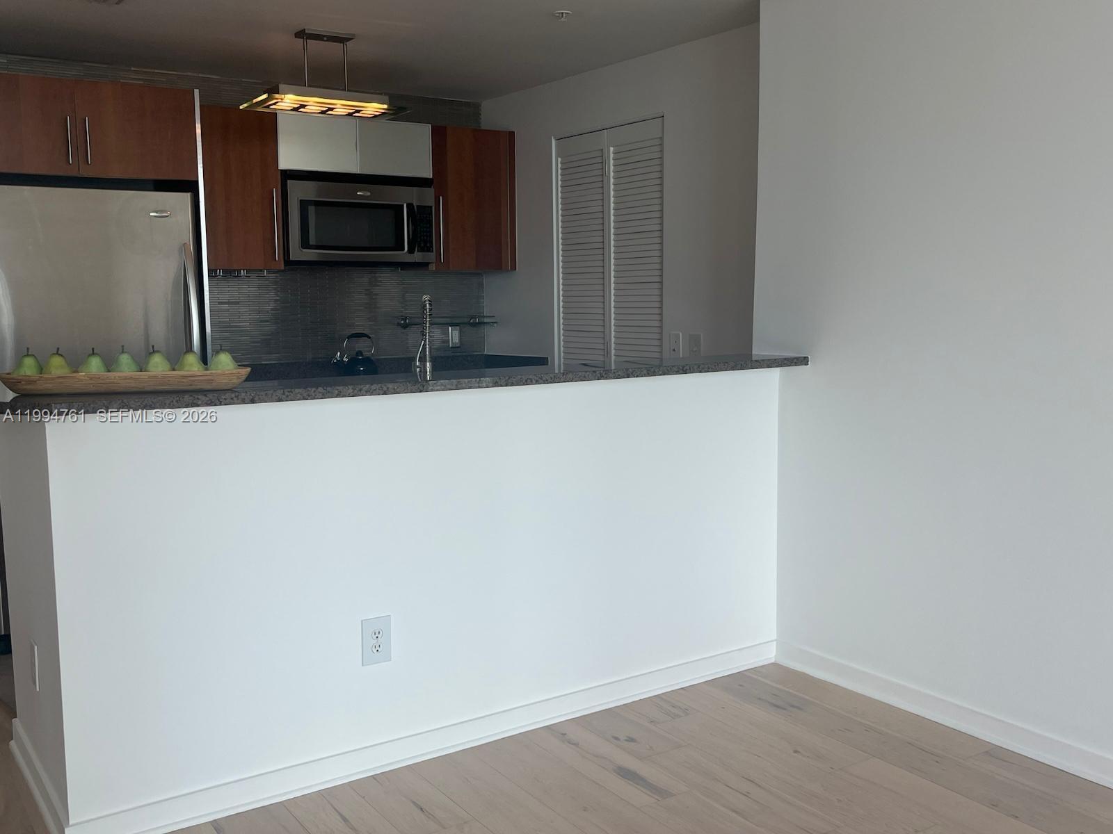 A kitchen features wood cabinets, stainless steel appliances, and a breakfast bar with pears — 300 S Biscayne Blvd # 2012, Miami FL 33131, MIAMI, FL
