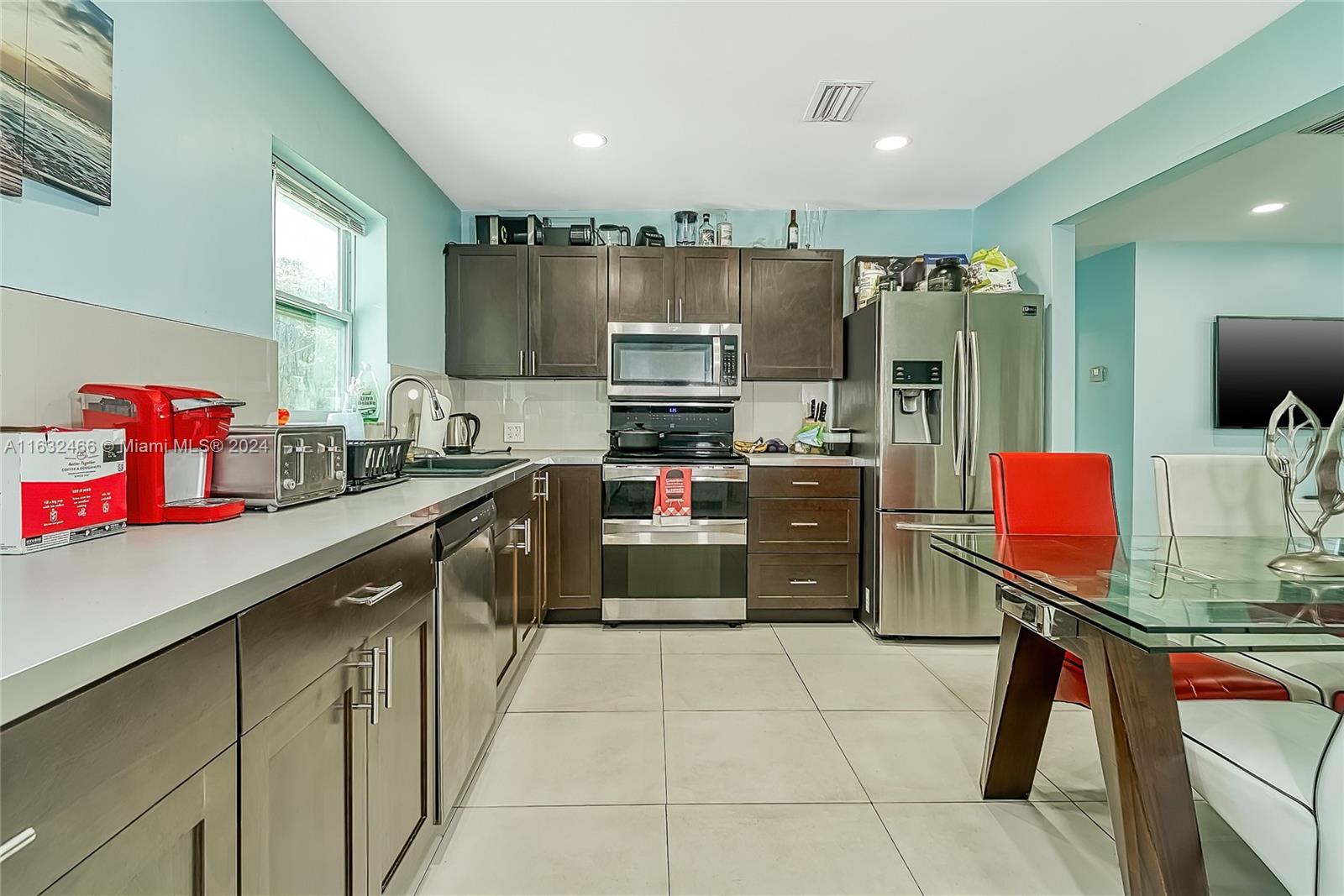 A kitchen features dark wood cabinets, stainless steel appliances, and light blue walls — 216 SW 6th St, Hallandale Beach FL 33009, HALLANDALE BEACH, FL