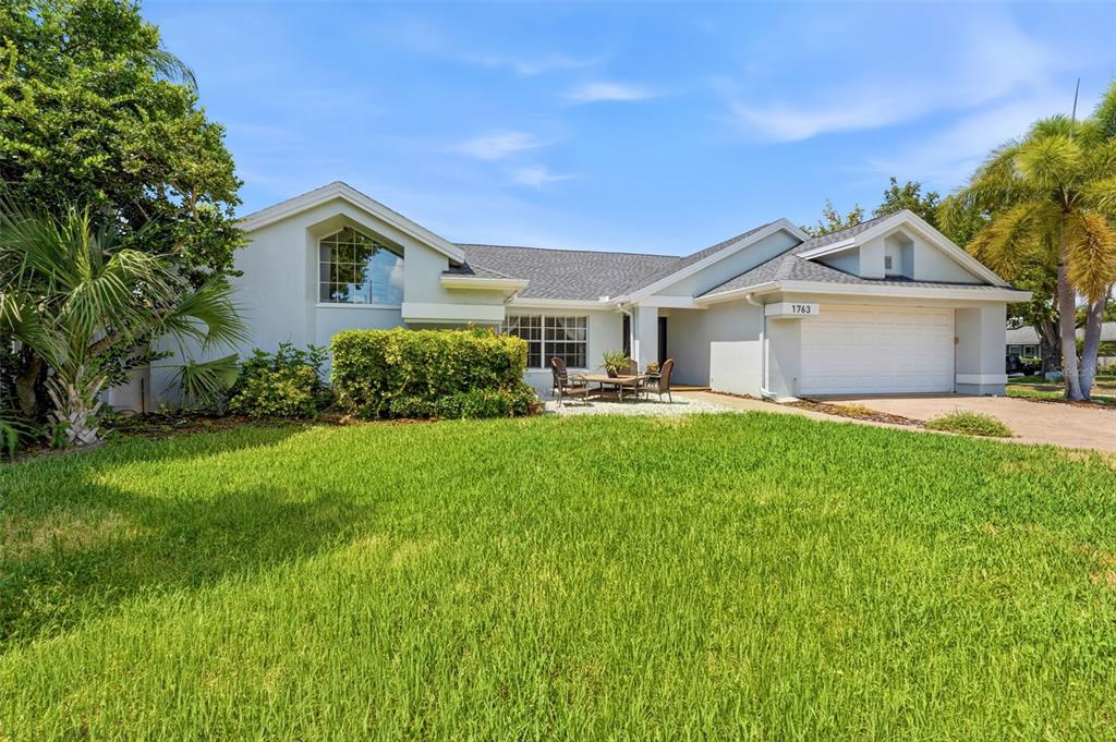 A single-story house with a white exterior, a two-car garage, and a front lawn — 1763 PEBBLE HILL COURT, PALM HARBOR, FL