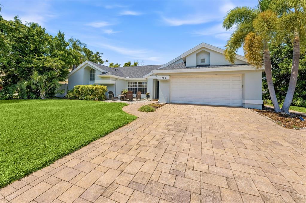 A single-story house with a paved driveway, two-car garage, and a small front patio area — 1763 PEBBLE HILL COURT, PALM HARBOR, FL