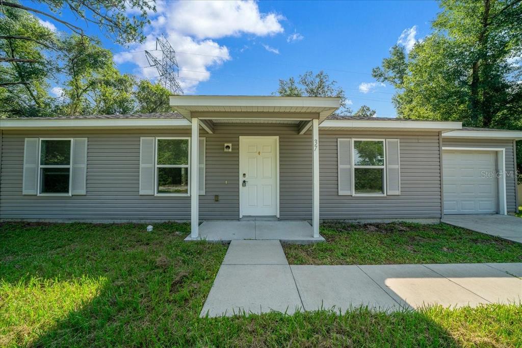 A single-story house with gray horizontal siding, a white front door, and an attached garage — 37 WATER TRACK COURSE, OCALA, FL
