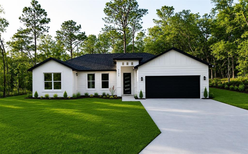 A white single-story house with a black roof and garage sits on a grassy lawn — 1133 W NANKEEN DRIVE, DUNNELLON, FL