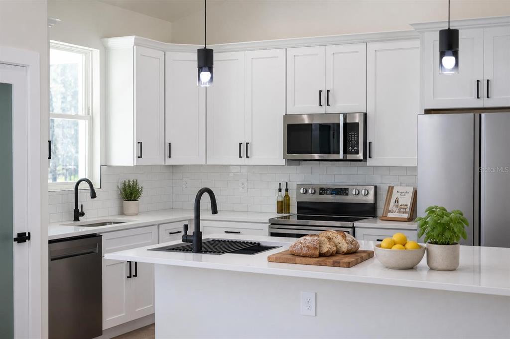 A modern kitchen features white cabinets, stainless steel appliances, a kitchen island, and subway tile — 1133 W NANKEEN DRIVE, DUNNELLON, FL