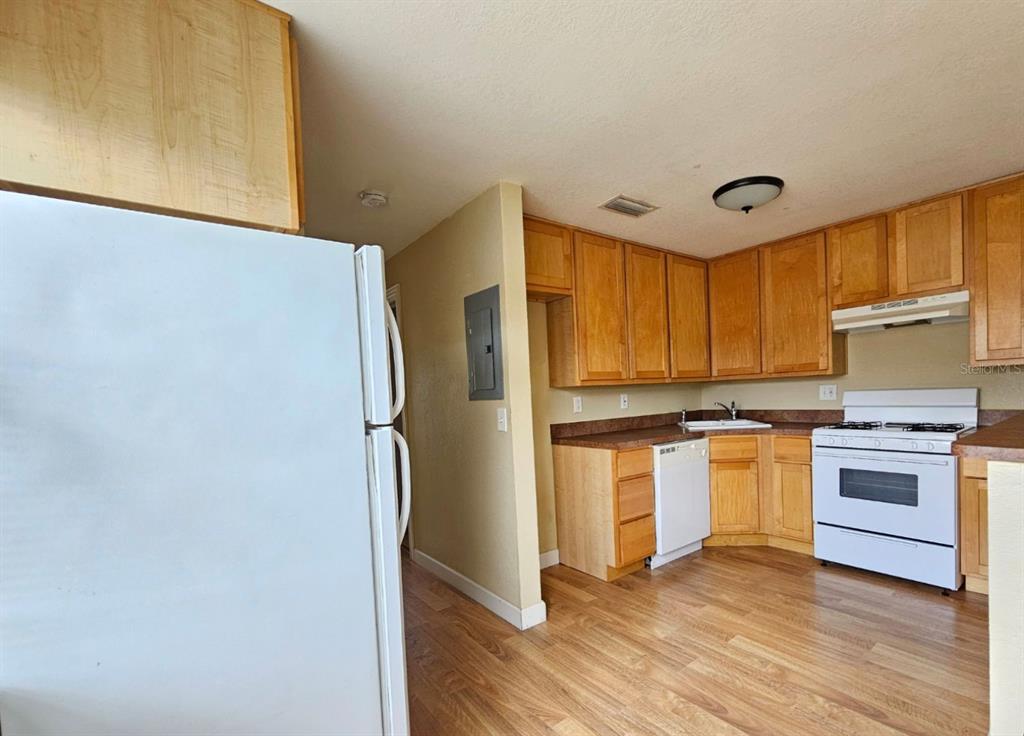 A kitchen features light wood cabinets, white appliances, and wood-look flooring — 117 N EVERGREEN AVENUE UNIT 201, CLEARWATER, FL