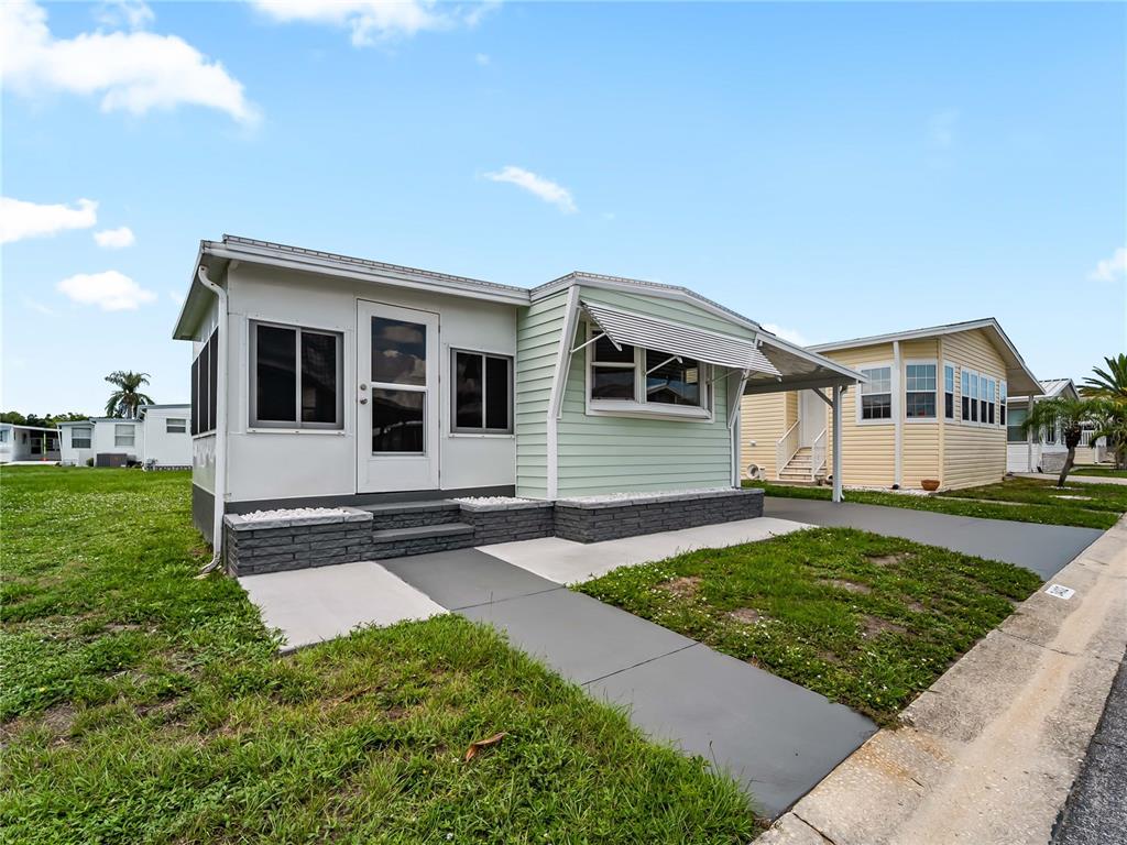 A light green mobile home with a white enclosed porch and a concrete driveway — 3402 SHINGLE OAK TERRACE, SARASOTA, FL