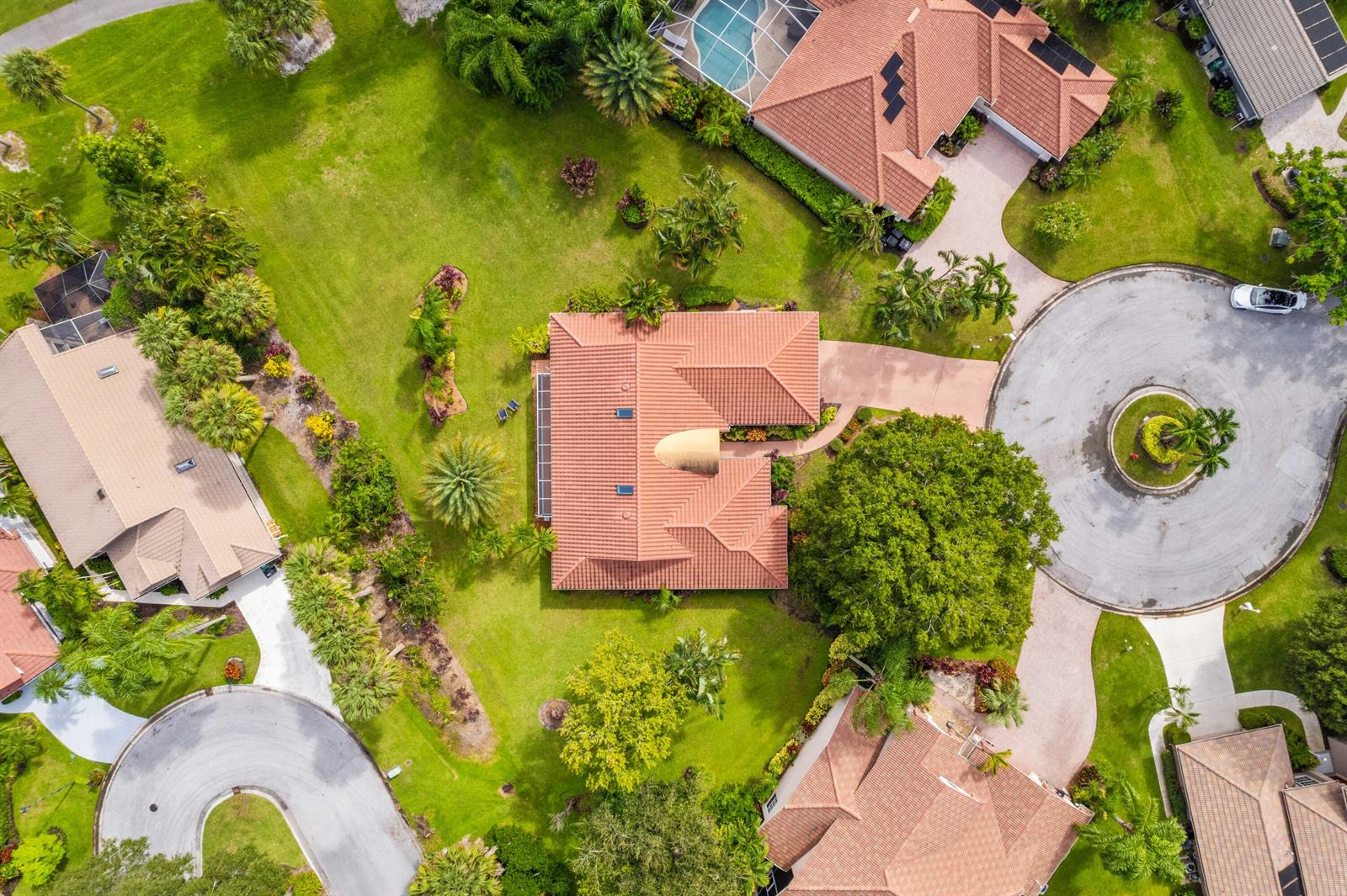 An aerial view shows several suburban homes with tile roofs, lush landscaping, and paved driveways — PORT ST. LUCIE, FL