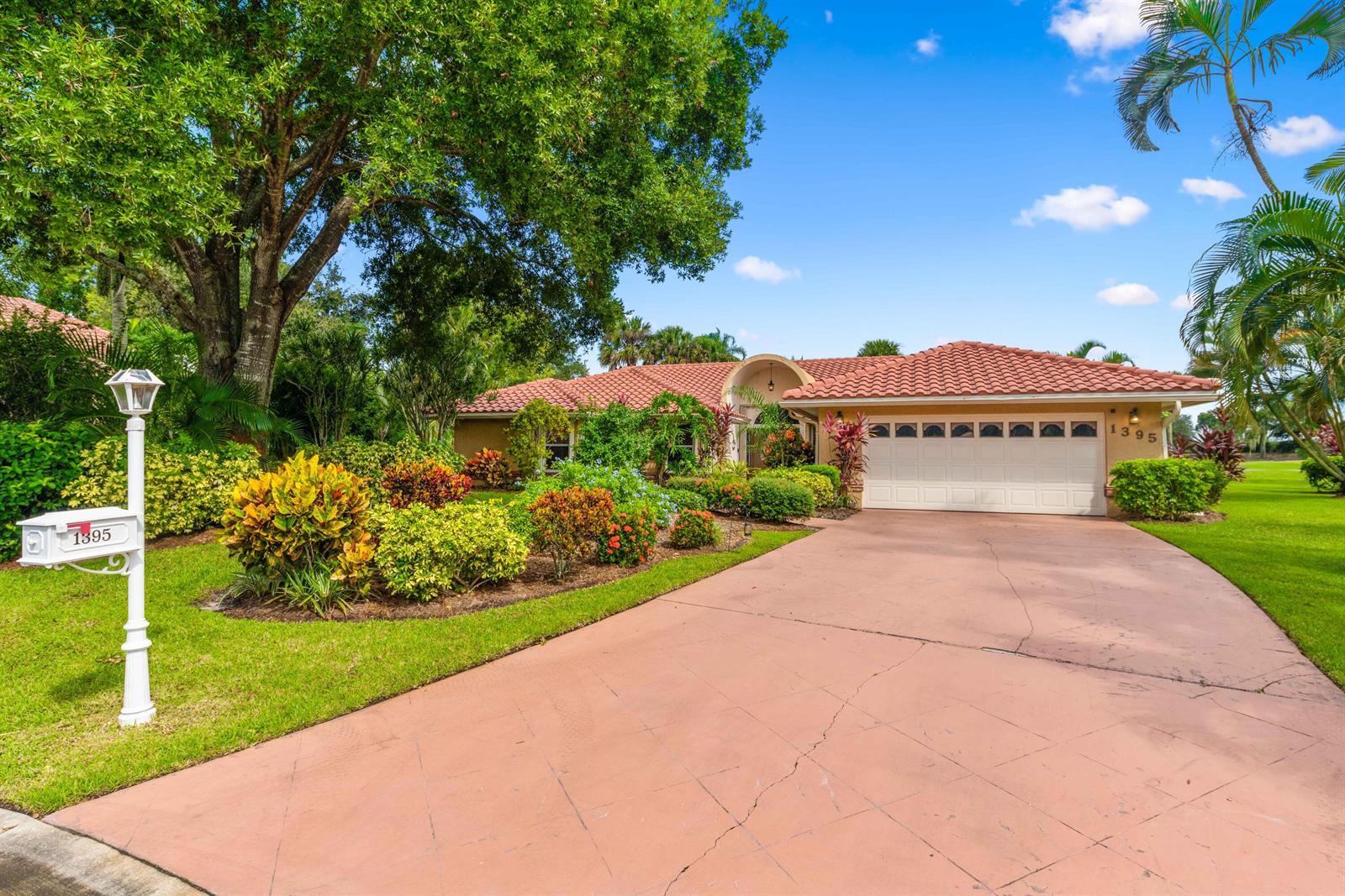 A single-story house with a tile roof, white garage door, and landscaped front yard — PORT ST. LUCIE, FL