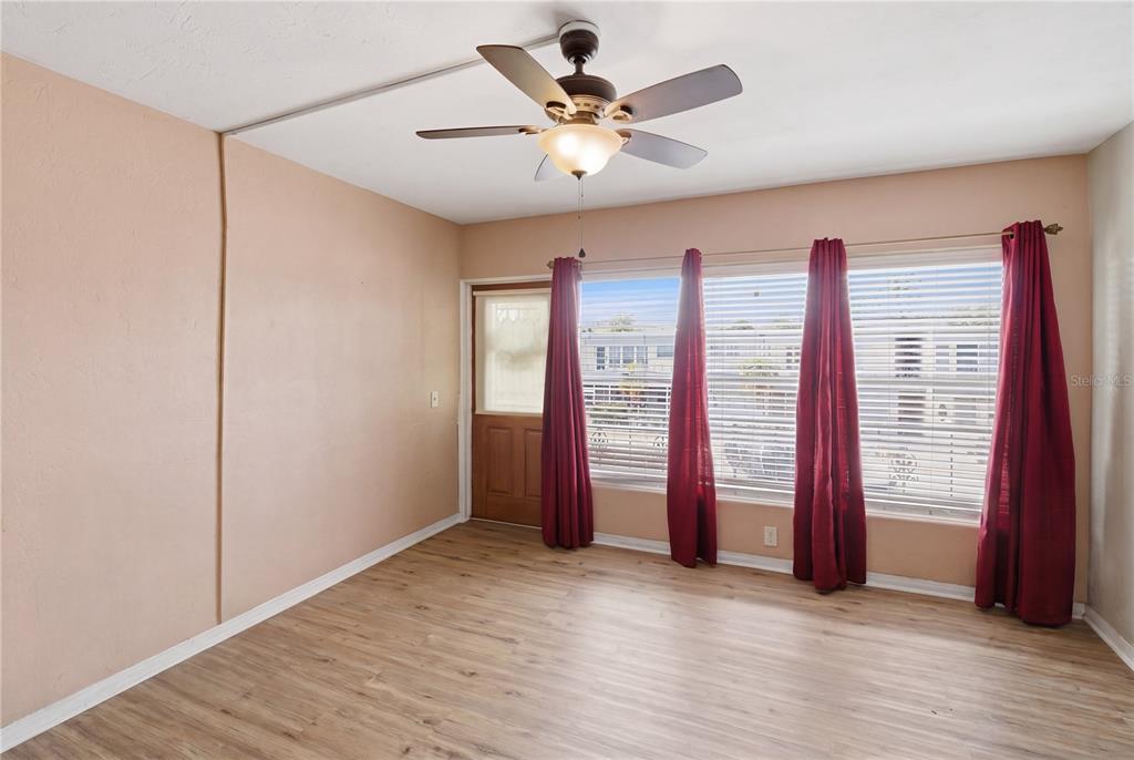 A living room features a grey sofa, green armchair, wood coffee table, and red curtains — 4325 58TH WAY N UNIT 1525, KENNETH CITY, FL