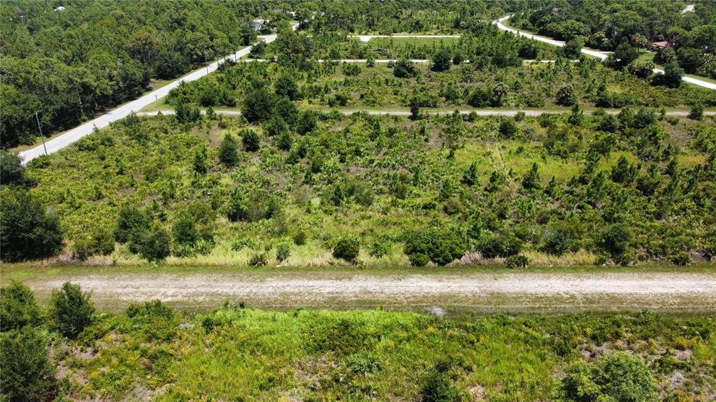 An aerial view shows a large, undeveloped plot of land with scattered trees and vegetation — 13214 ARMOUR DRIVE, PUNTA GORDA, FL