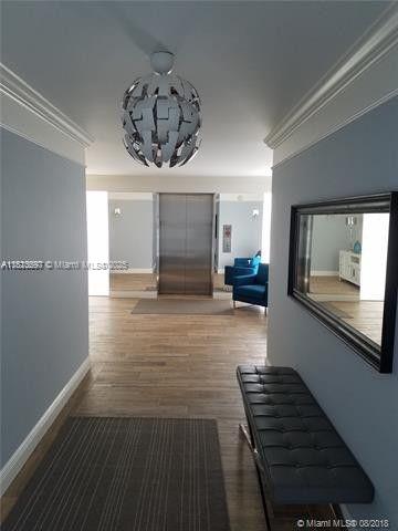 A hallway with light blue walls, a modern pendant light, and a black tufted bench — 2505 S Ocean Blvd # 2070, Palm Beach FL 33480, PALM BEACH, FL