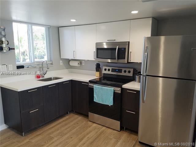 A modern kitchen features dark lower cabinets, white upper cabinets, and stainless steel appliances — 2505 S Ocean Blvd # 2070, Palm Beach FL 33480, PALM BEACH, FL
