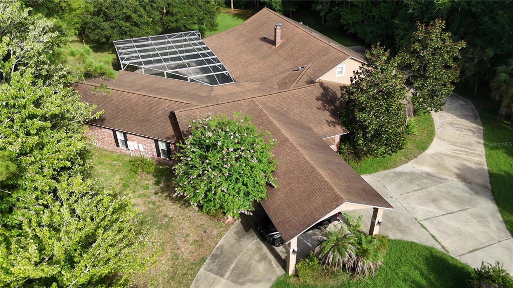 An aerial view shows a house with a brown shingled roof, a screened-in pool, and a carport — 2083 BILTMORE POINT, LONGWOOD, FL